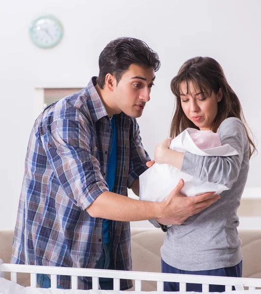 Young parents with their newborn baby near bed cot — Stock Photo, Image