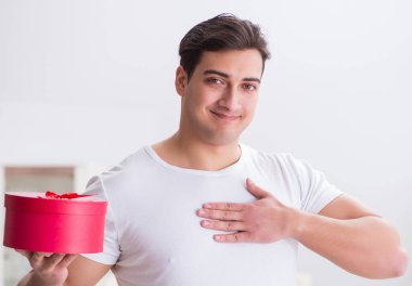 Evde hediye çantası taşıyan genç bir adam karısına sürpriz hazırlıyor.