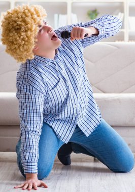 Evde karaoke yapan komik adam.