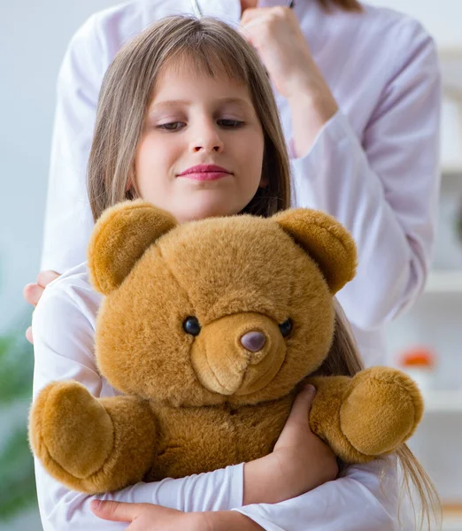 Mujer médico femenino examinando poco linda chica con juguete oso — Foto de Stock