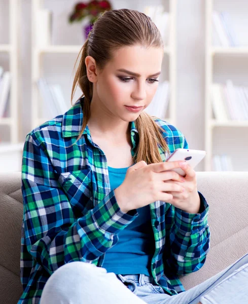 Estudante feminina sentada no sofá com celular — Fotografia de Stock