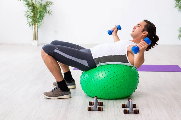 Young handsome man doing sport exercises indoors — Stock Photo, Image