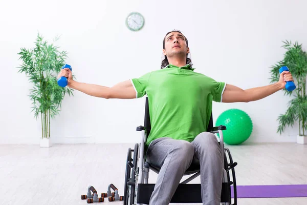 Jeune homme en fauteuil roulant faisant des exercices à l'intérieur — Photo