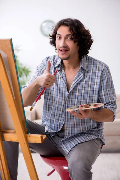 Молодой красивый мужчина наслаждается живописью дома — стоковое фото