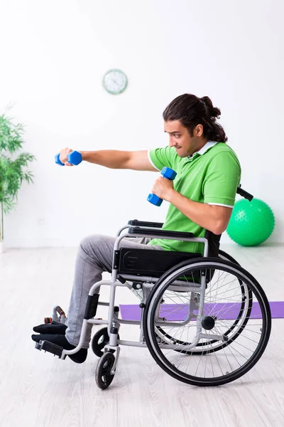 Молодой человек в инвалидной коляске делает упражнения в помещении — стоковое фото