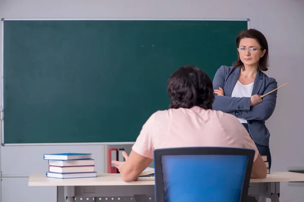 Oude vrouwelijke leraar en mannelijke student in de klas — Stockfoto