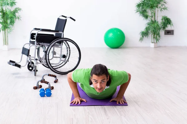 Young man in wheel-chair doing exercises indoors