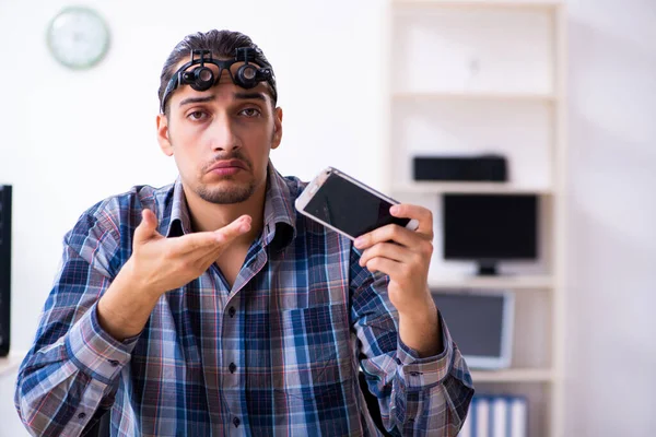 Young handsome technician repairing mobile phone