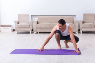 Genç adam evde antrenman ve egzersiz yapıyor.