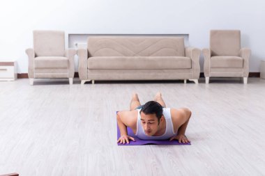 Genç adam evde antrenman ve egzersiz yapıyor.