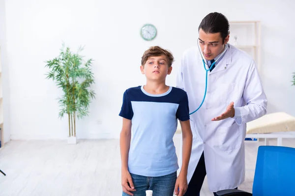 Jeune homme médecin examinant garçon à la clinique — Photo