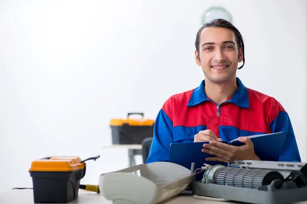 Jovem reparador reparando ar-condicionado no centro de garantia — Fotografia de Stock