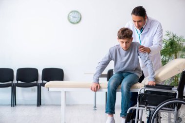 Genç erkek doktor pediatrist ve tekerlekli sandalyedeki çocuk.