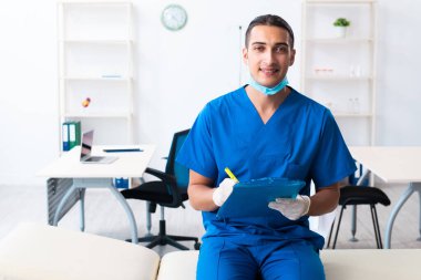 Klinikte çalışan genç erkek doktor.