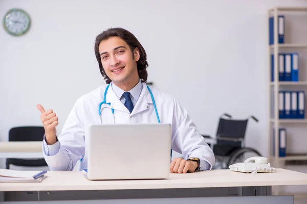 Młody przystojny lekarz pracujący w klinice — Zdjęcie stockowe