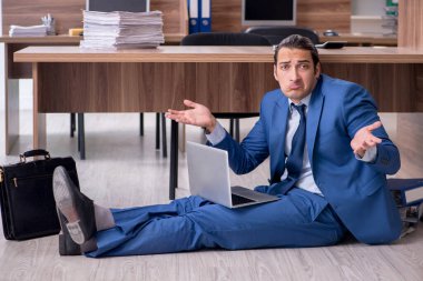 Genç bir erkek işçi ve ofiste çok fazla iş var.