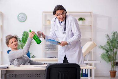 Alkolik kadın, genç erkek doktoru ziyaret ediyor.