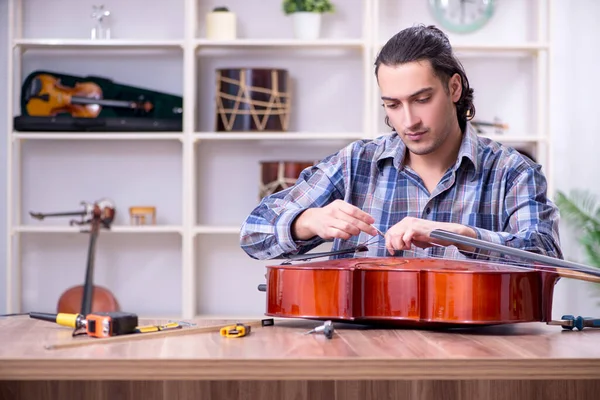 Jeune beau réparateur réparer violoncelle — Photo