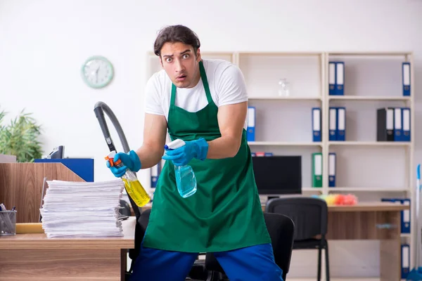 Jovem empreiteiro bonito limpando o escritório — Fotografia de Stock