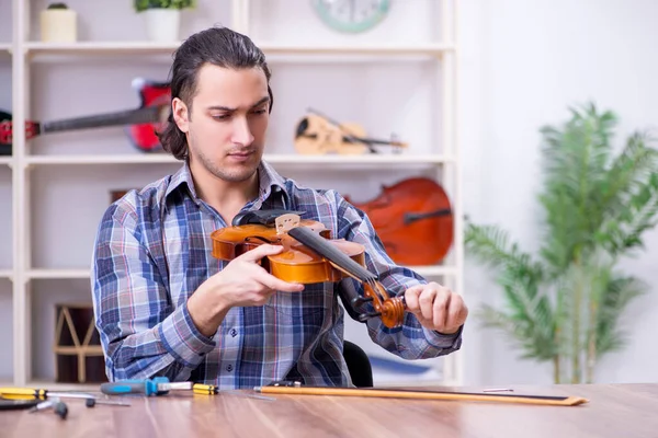 Jovem reparador bonito reparando violino — Fotografia de Stock