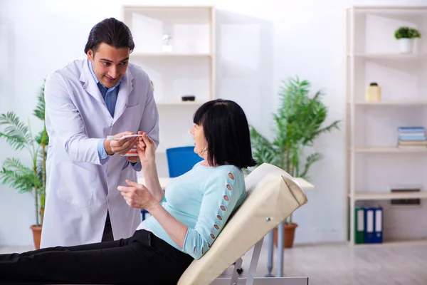 Mulher velha visitando jovem médico dentista — Fotografia de Stock