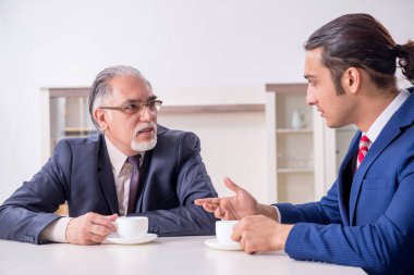 İki işadamı ofiste iş konuşuyor.