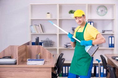 Genç müteahhit ofisi temizliyor.