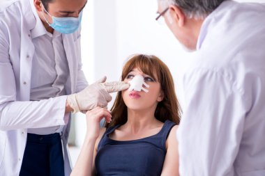 Plastik cerrahi konseptinde iki erkek doktor ve genç kadın.
