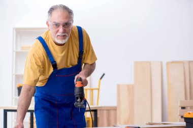 Yaşlı erkek marangoz atölyede çalışıyor.