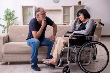 Yaşlı koca engelli eşine bakıyor.