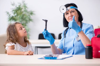 Küçük kız yaşlı kadın doktoru ziyaret ediyor.