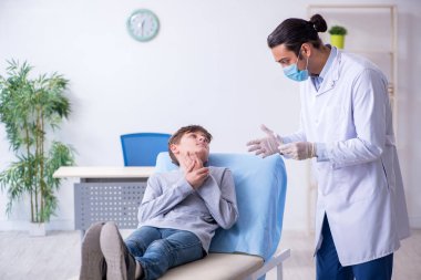 Genç çocuk hastanede doktoru ziyaret ediyor.