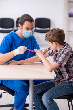 Genç çocuk hastanede doktoru ziyaret ediyor.