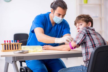 Genç çocuk hastanede doktoru ziyaret ediyor.