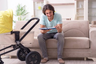 Bebek arabasında bebeğe bakan genç adam.