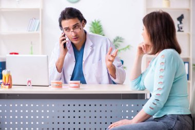 Orta yaşlı bir kadın, erkek doktor stomatoloğu ziyaret ediyor.