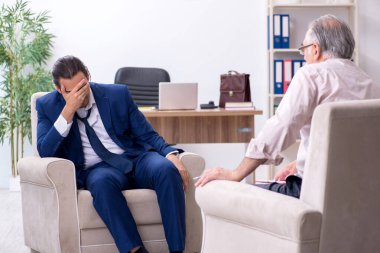 Genç adam yaşlı erkek doktor psikologunu ziyaret ediyor.