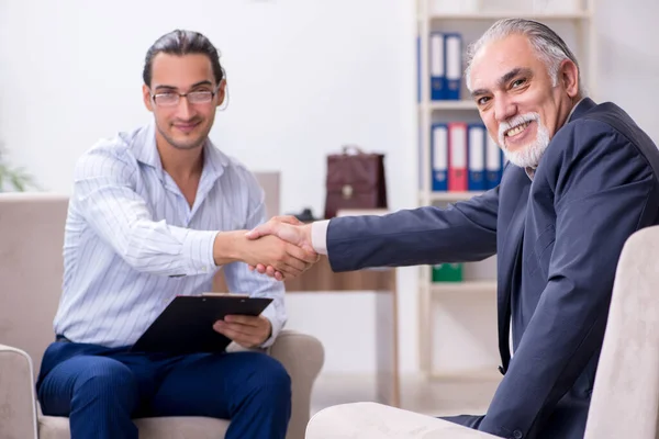 Homem velho visitando jovem médico psicólogo masculino — Fotografia de Stock