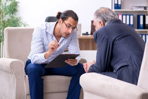 Oude man op bezoek bij jonge mannelijke dokter psycholoog — Stockfoto