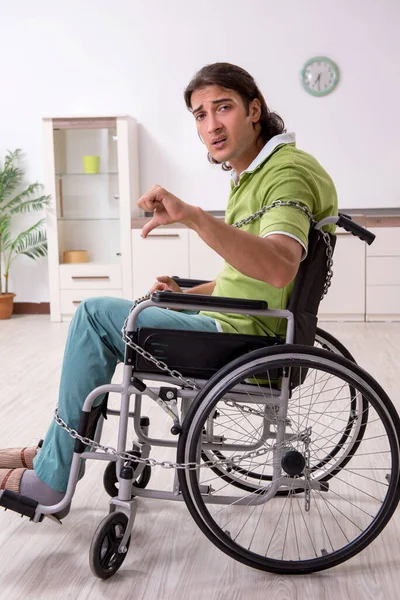 Mladý muž invalidní v invalidním vozíku trpí doma — Stock fotografie