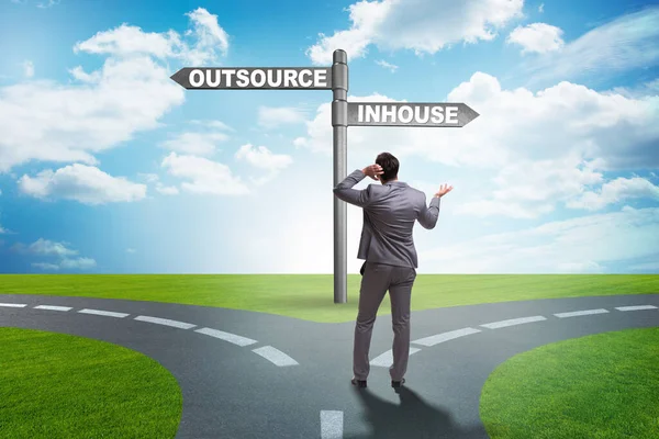 Businessman at crossroads deciding between outsourcing and inhou — Stock Photo, Image