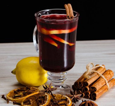 Sıcak şarap, yılbaşı masasında servis edilen bardaklarda parıldıyor.