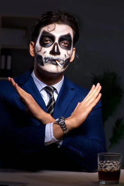 Бізнесмен з лякаючою маскою для обличчя, що працює пізно в офісі — стокове фото