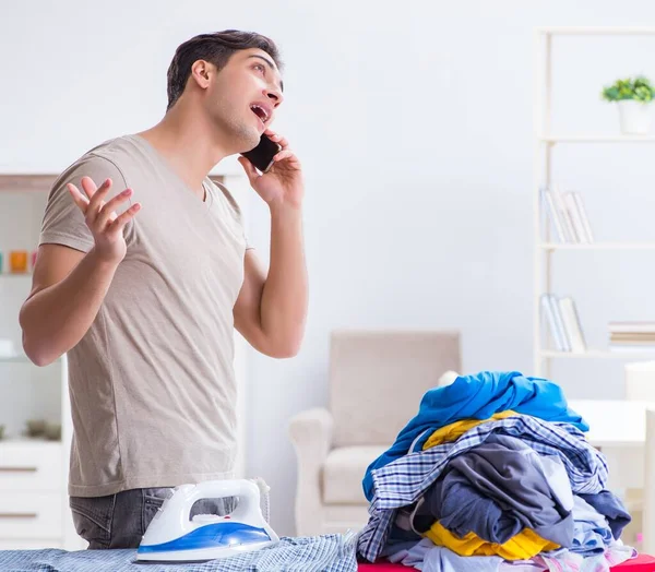 Joven marido haciendo planchado de ropa en casa — Foto de Stock