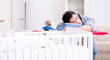 Genç baba yeni doğan bebeğe bakıyor.