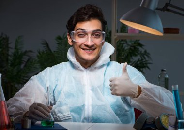 Genç erkek kimyager gece geç saatlerde fazla mesai yapıyor.