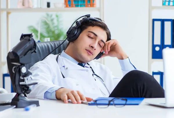 Happy excited doctor listening to music during lunch break in ho