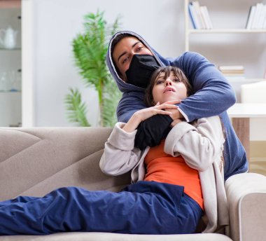 Silahlı adam evde genç bir kadına saldırıyor.