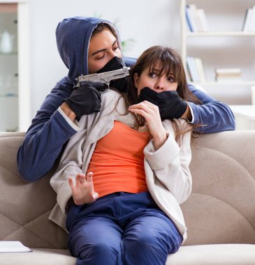 Silahlı adam evde genç bir kadına saldırıyor.