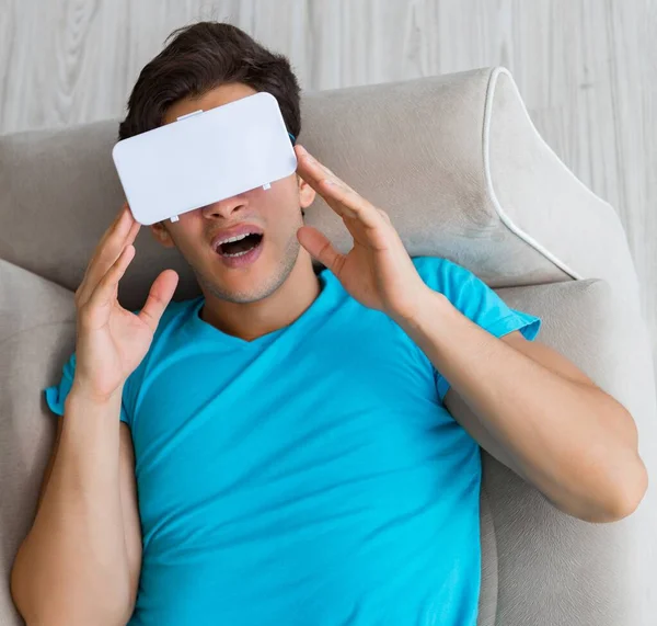 年轻男子戴着VR眼镜躺在沙发上休息 — 图库照片